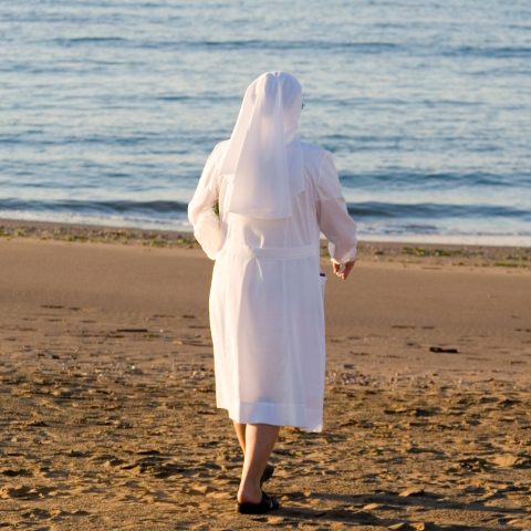 Una suora in spiaggia Canva