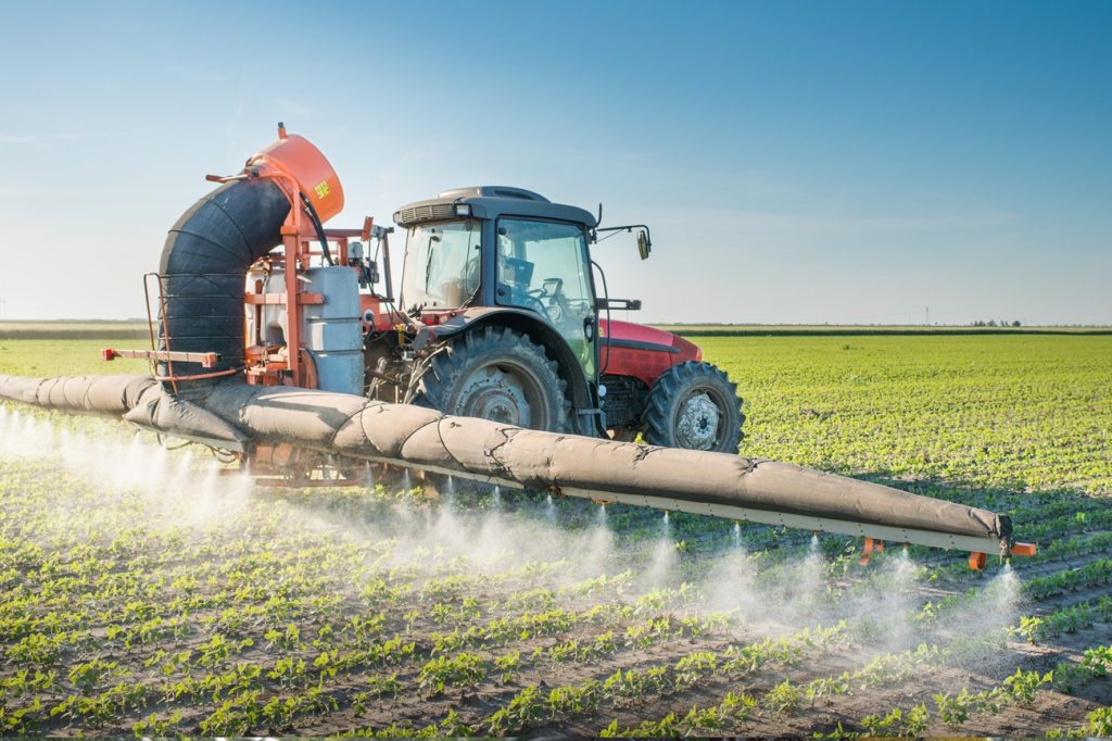 Mezzo agricolo diffonde pesticidi su un campo