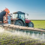 Mezzo agricolo diffonde pesticidi su un campo