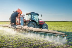 Mezzo agricolo diffonde pesticidi su un campo