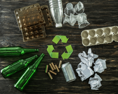 Bottiglie di vetro, lattina, carta, plastica, cartone e simbolo del riciclo