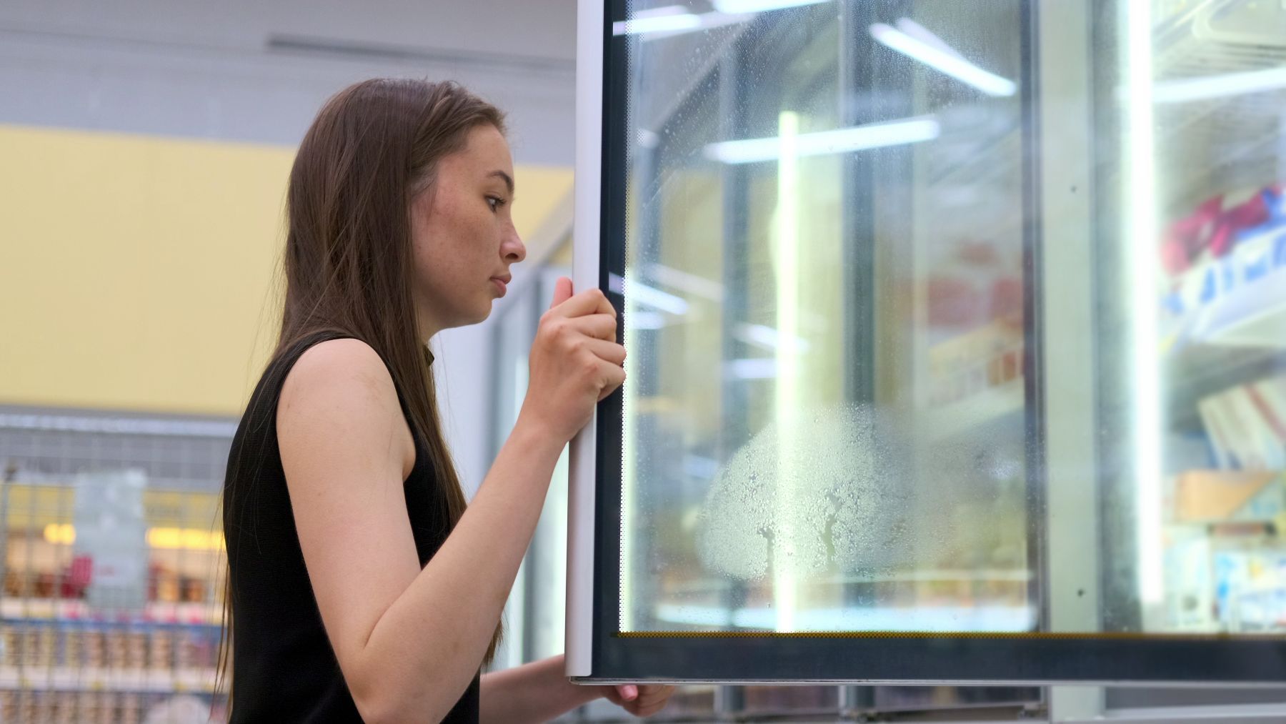 Young brunette taking ice cream from the fridge Storyblocks