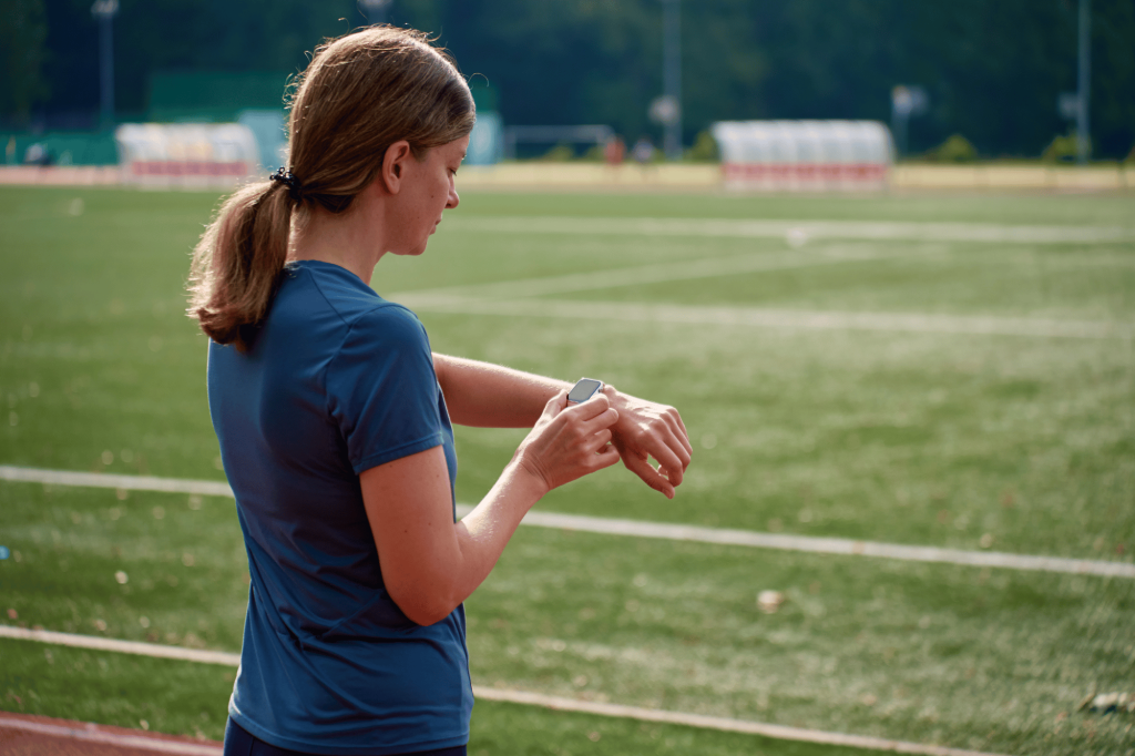 Donna che controlla lo smartwatch durante una corsa su una pista sportiva