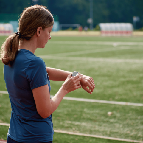 Donna che controlla lo smartwatch durante una corsa su una pista sportiva