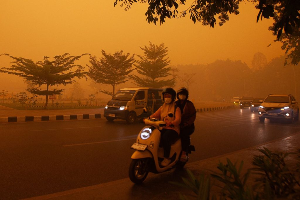 Automobilisti si recano al lavoro in una mattinata avvolta da una fitta coltre di fumo causata dagli incendi boschivi in Indonesia