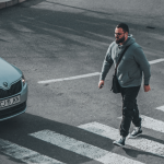 uomo attraversa strisce pedonali mentre arriva macchina